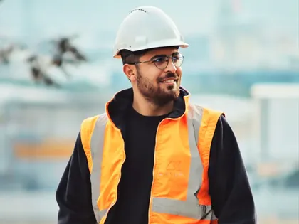 Ouvrier du bâtiment en casque et gilet orange sur un chantier