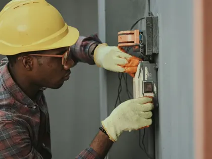 Électricien en casque jaune devant un coffret électrique