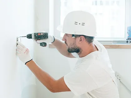 Ouvrier en casque qui perce un mur