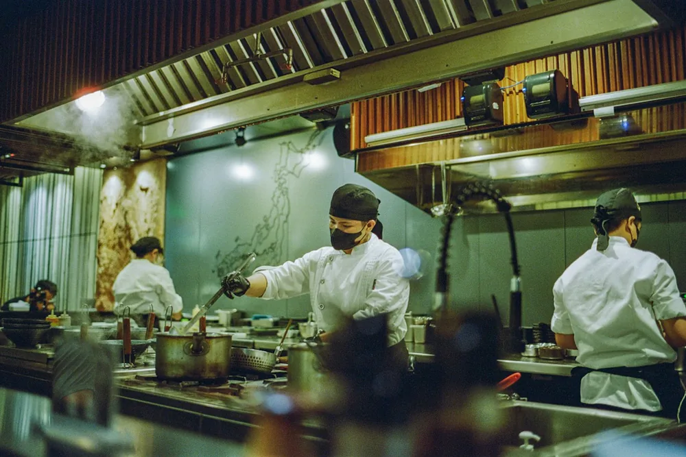 Cuisiniers au travail dans la cuisine ouverte d'un restaurant
