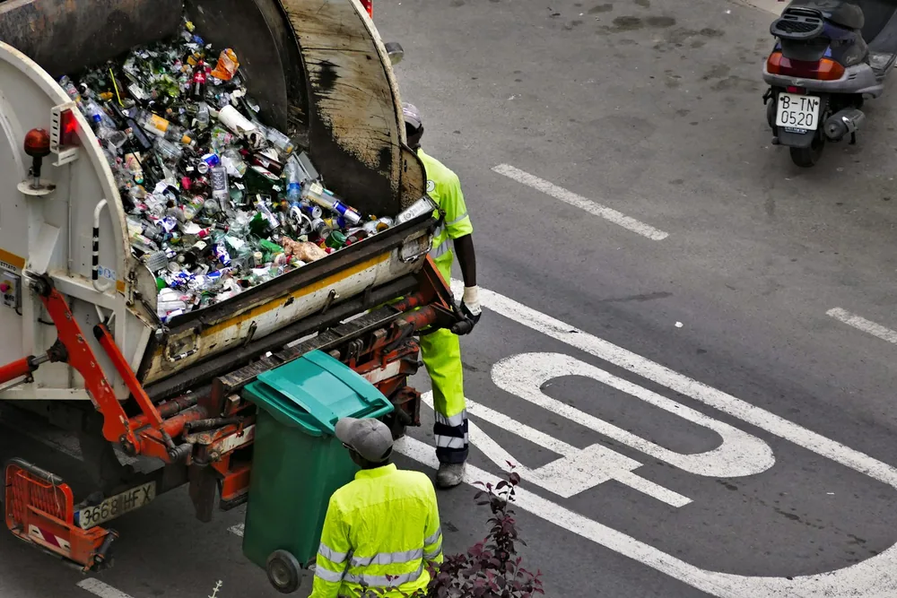 Éboueurs et camion de collecte vidant des conteneurs dans une rue