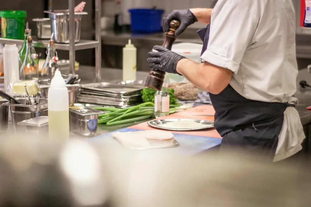 Cuisinier en tenue noire dressant des plats dans une cuisine professionnelle
