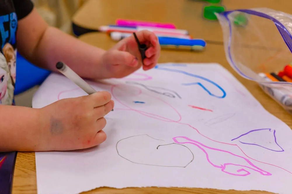 Enfant qui dessine au feutre sur une feuille