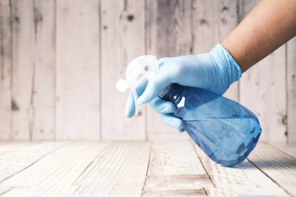 Mains gantées tenant un flacon pulvérisateur de produit nettoyant