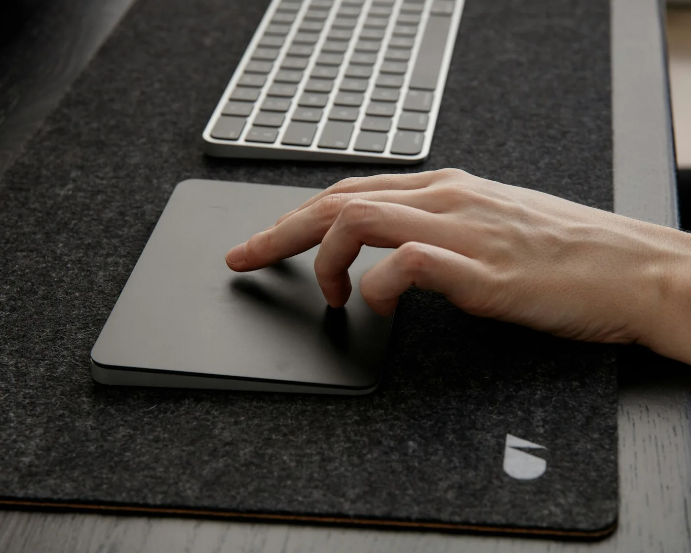 Main posée sur un pavé tactile, à côté d'un clavier, sur un bureau